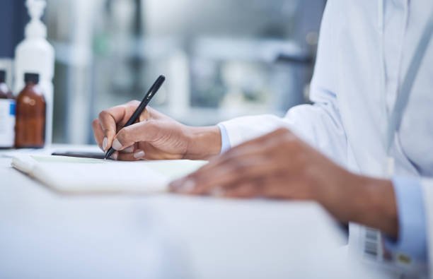 A researcher in a lab coat documenting mecfs findings in a notebook.