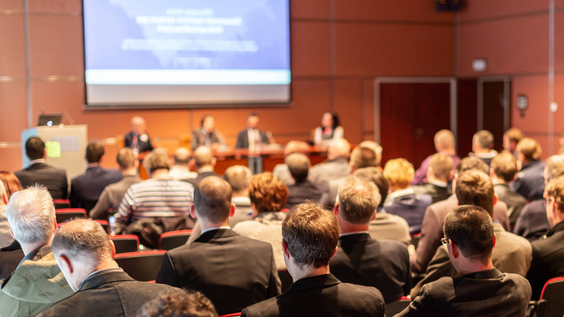 A large group of individuals with mecfs sitting in a conference room.
