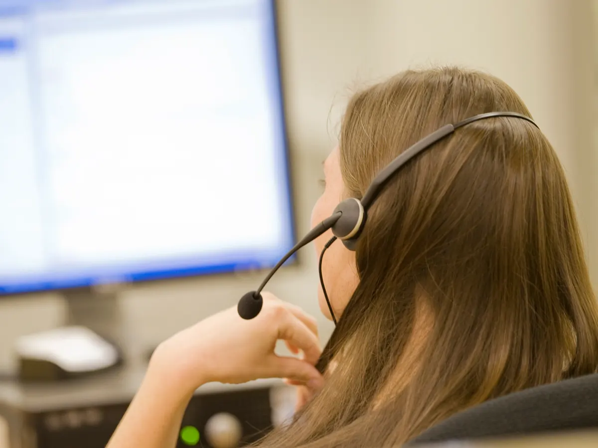 A woman with mecfs wearing a headset in front of a computer.