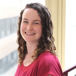 A woman with mecfs smiling in front of a window.