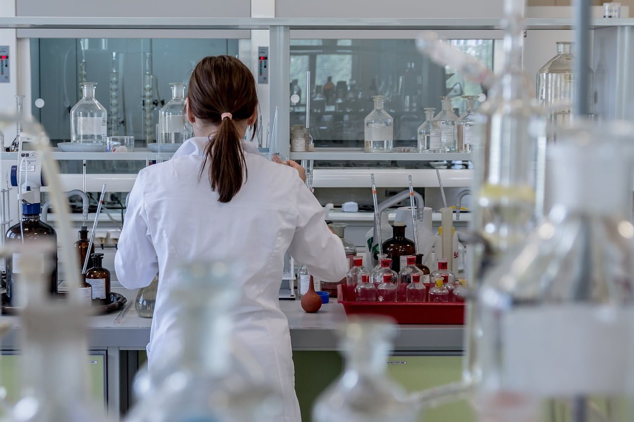 A woman conducting experiments in a laboratory with an abundance of bottles, studying mecfs.