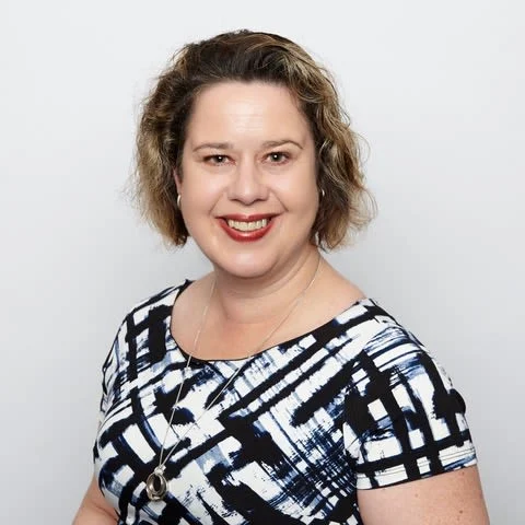 A smiling woman in a black and white dress with mecfs.