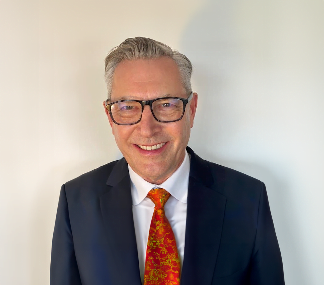 A man with MECFS in a suit and tie smiling.