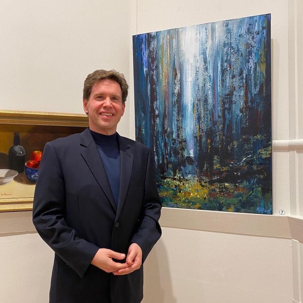 A man with ME/CFS standing in front of a painting.