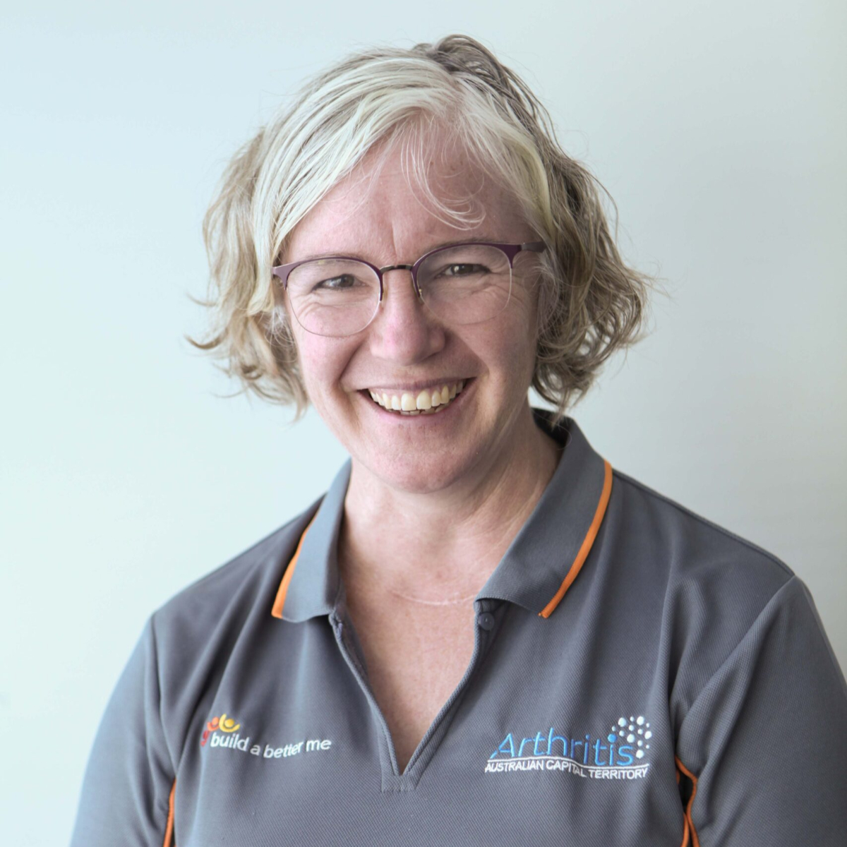 A smiling woman wearing a grey polo shirt.