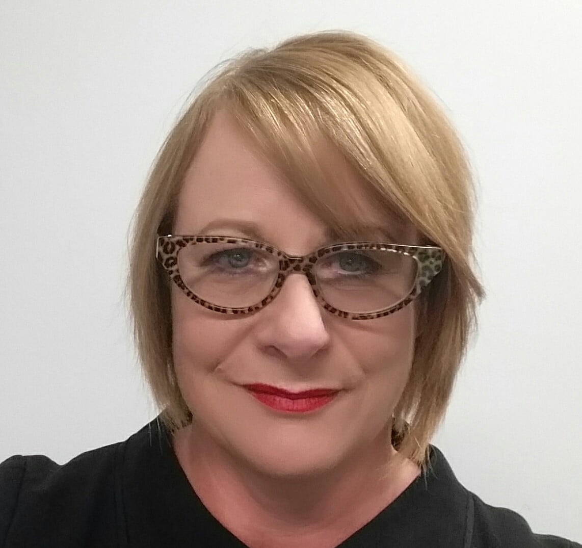 A woman in leopard print glasses wearing a black shirt advocates for mecfs.