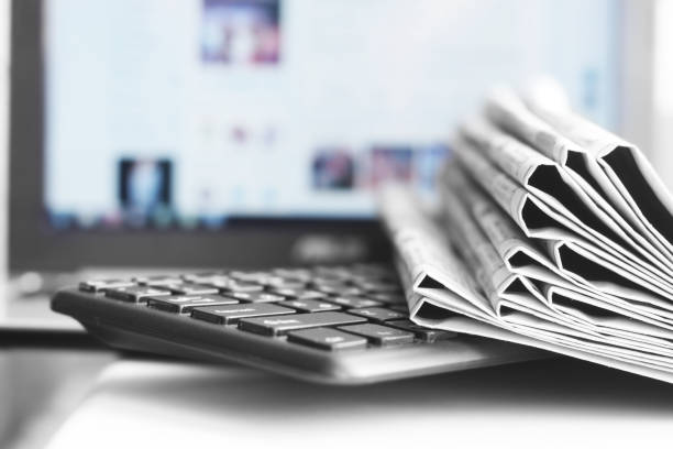 A stack of newspapers placed on top of a laptop, emphasizing the topic of mecfs.