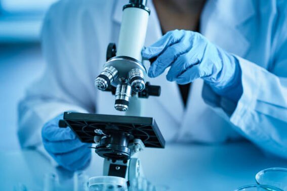 A mecfs researcher examining samples through a microscope in a laboratory.